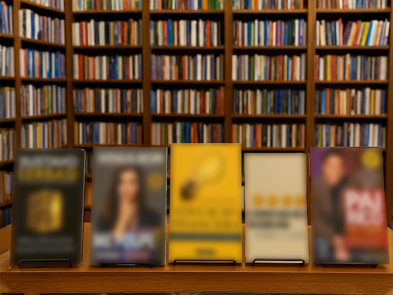Fotografia realista de cinco livros de finanças pessoais expostos lado a lado sobre uma estante de madeira em uma livraria, com prateleiras de livros ao fundo. As capas visíveis incluem títulos de Gustavo Cerbasi, Nathalia Arcuri, José Pio Martins, George S. Clason e Robert T. Kiyosaki.